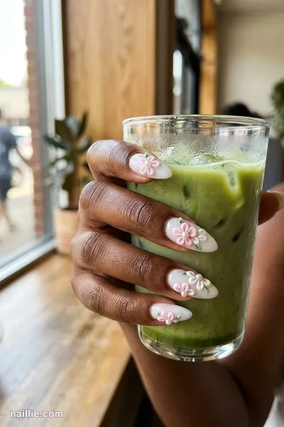 Close-up of almond nails with tiny raised 3D flowers on a milky base — look 2