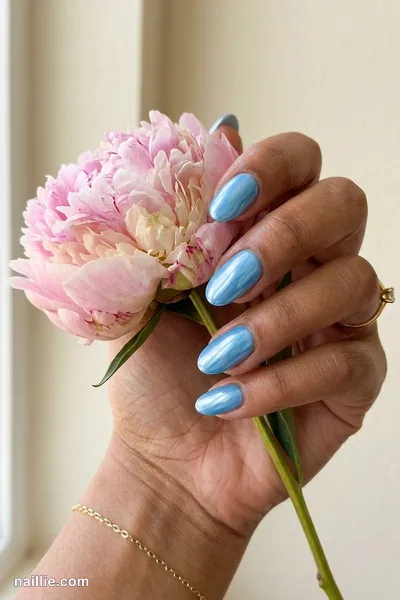 Close-up of oval nails with baby blue polish and a mirror-like chrome finish