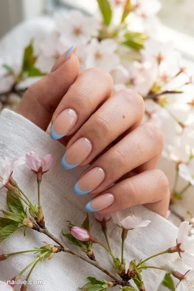 Close-up of almond nails with baby blue French tips over a sheer nude base — look 2