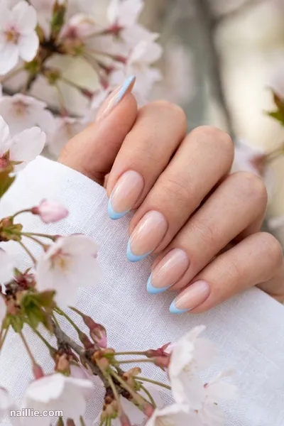 Close-up of almond nails with baby blue French tips over a sheer nude base — look 3