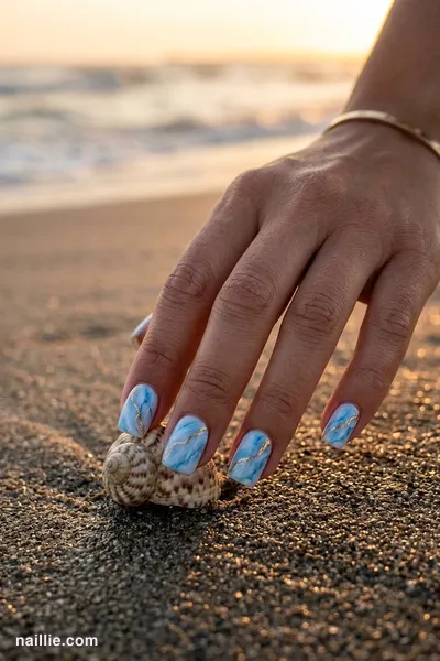 Close-up of short square nails with baby blue marble swirls with gold veins — look 2