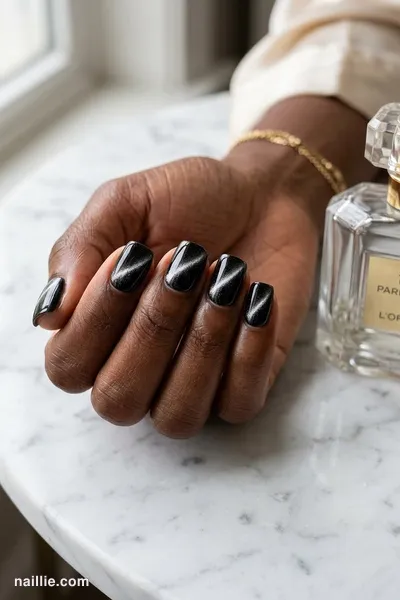Close-up of short square nails with black polish and a shimmering magnetic cat eye effect — look 2