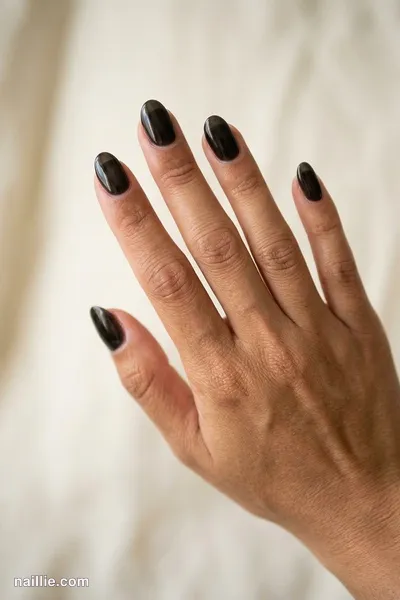 Close-up of oval nails with black polish and a glossy see-through jelly finish — look 2