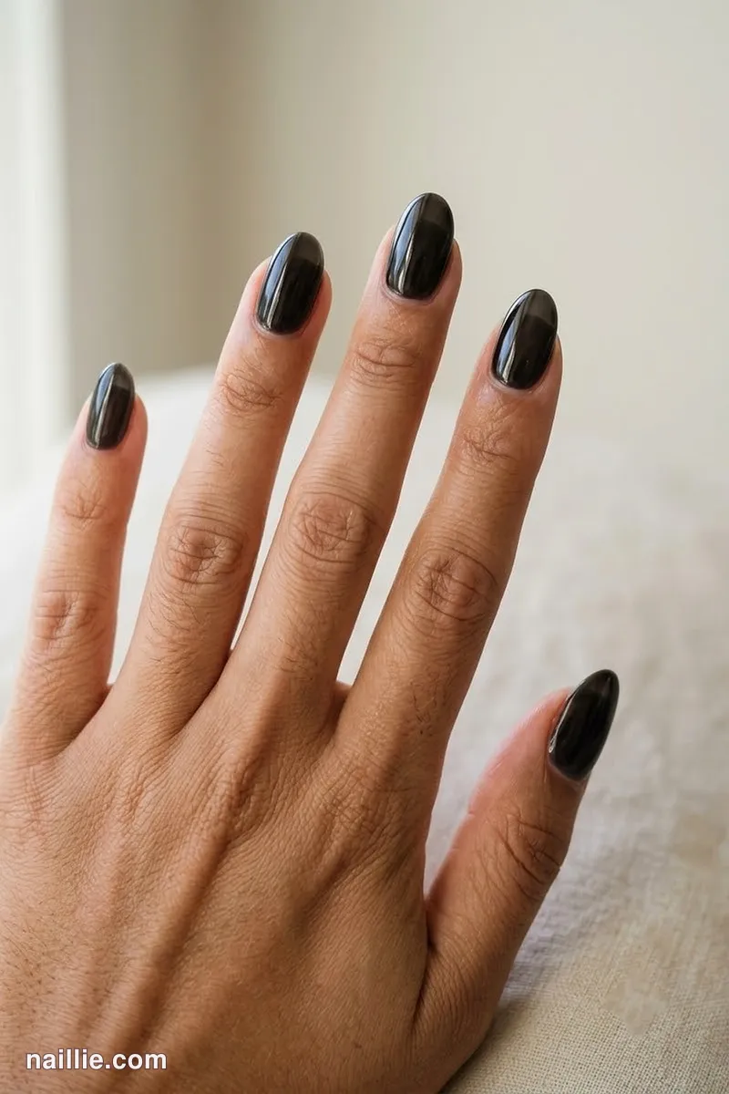 Close-up of oval nails with black polish and a glossy see-through jelly finish