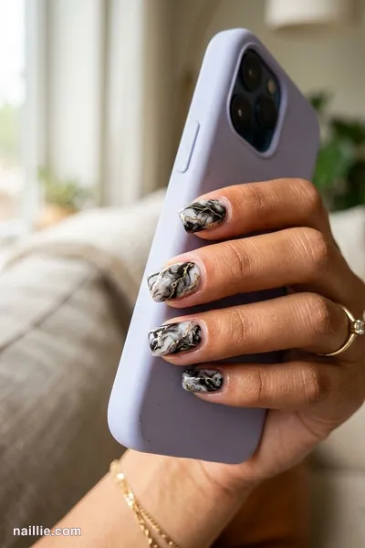 Close-up of short square nails with black marble swirls with gold veins — look 2