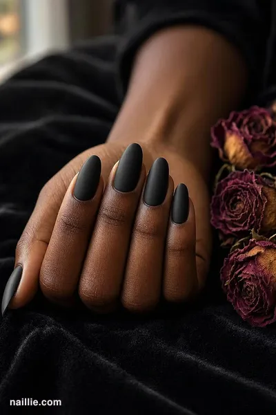 Close-up of almond nails with black polish and a soft matte top coat