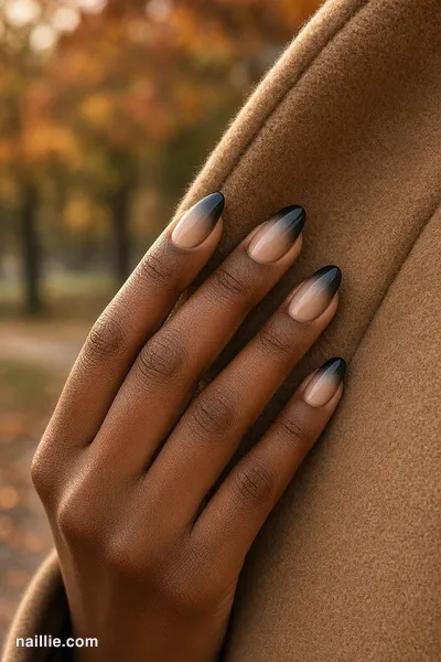 Close-up of almond nails with a black ombre fading into nude