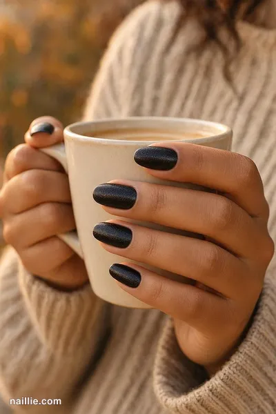 Close-up of oval nails with black polish and a soft velvet shimmer