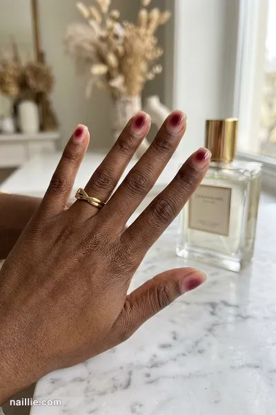 Close-up of short square nails with a glowing burgundy aura in the center — look 3