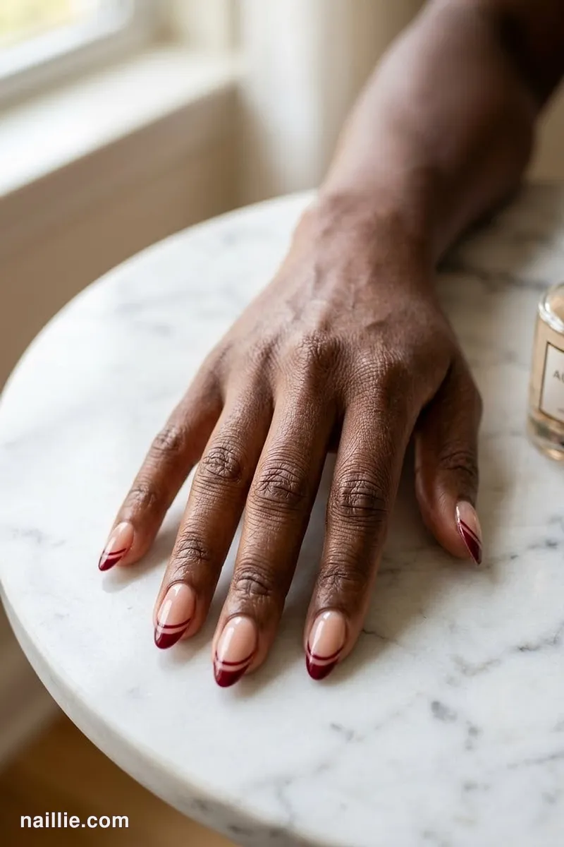 Close-up of almond nails with a burgundy double French line