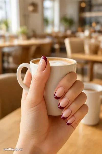 Close-up of oval nails with a burgundy double French line