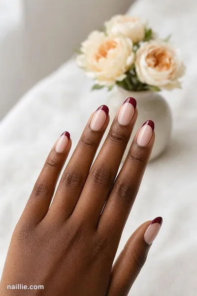 Close-up of almond nails with burgundy French tips over a sheer nude base — look 3