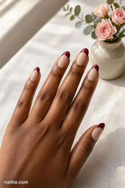 Close-up of almond nails with burgundy French tips over a sheer nude base — look 4