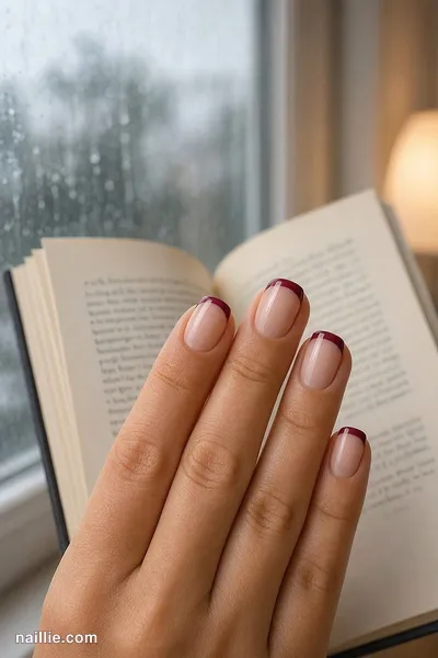 Close-up of short square nails with burgundy French tips over a sheer nude base — look 4