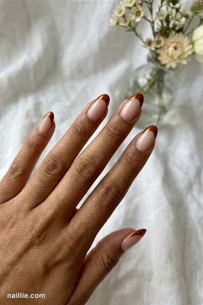 Close-up of oval nails with burnt orange chrome French tips