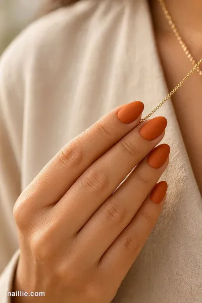 Close-up of almond nails with burnt orange polish and a soft matte top coat — look 3