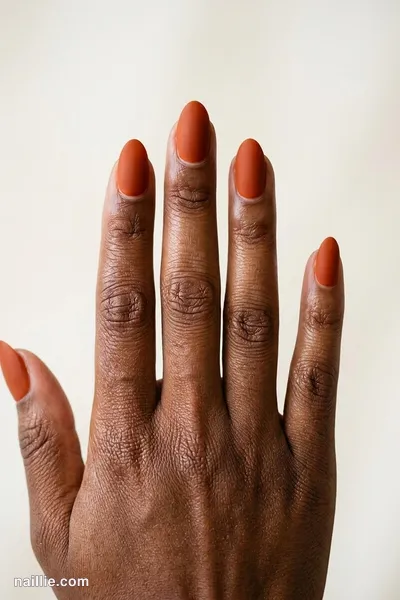 Close-up of short almond nails with burnt orange polish and a soft matte top coat — look 2