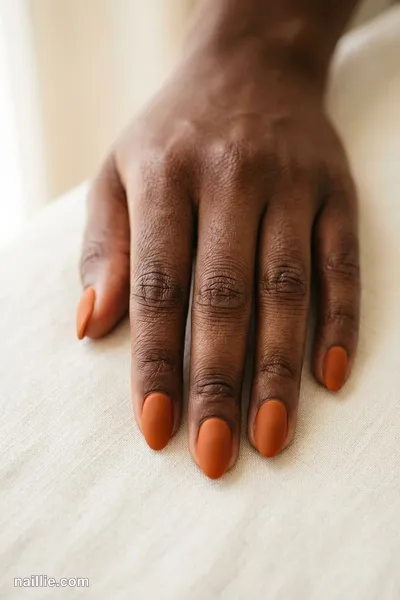 Close-up of short almond nails with burnt orange polish and a soft matte top coat — look 3