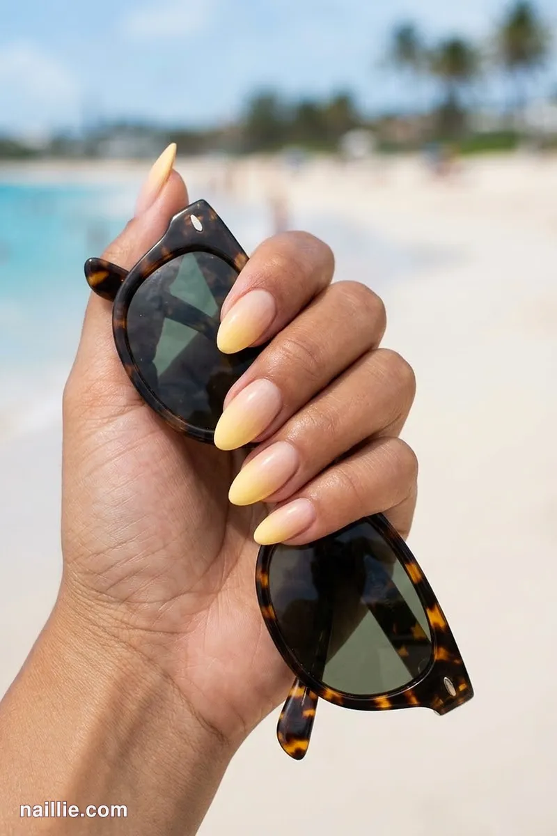 Close-up of almond nails with a butter yellow ombre fading into nude
