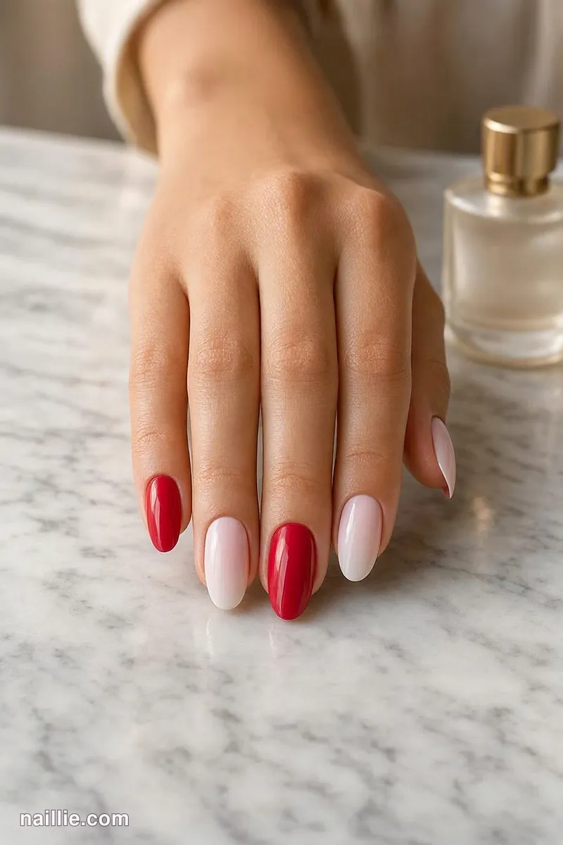 Close-up of almond nails with glossy cherry red nails mixed with milky pink ones