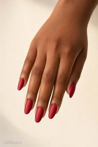 Close-up of almond nails with cherry red polish and a soft matte top coat
