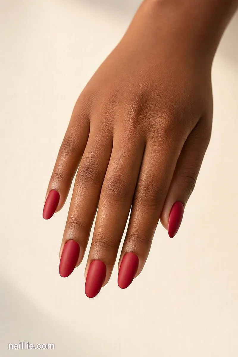 Close-up of almond nails with cherry red polish and a soft matte top coat