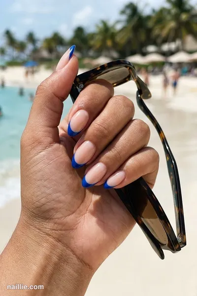 Close-up of almond nails with cobalt blue French tips over a sheer nude base — look 2