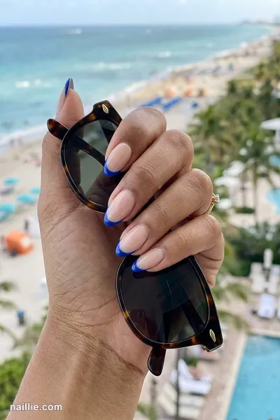 Close-up of almond nails with cobalt blue French tips over a sheer nude base — look 3