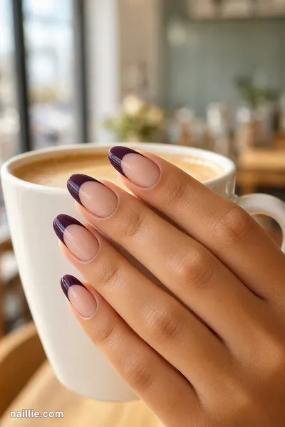Close-up of almond nails with a deep plum double French line