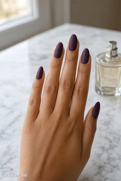 Close-up of almond nails with deep plum polish and a soft matte top coat