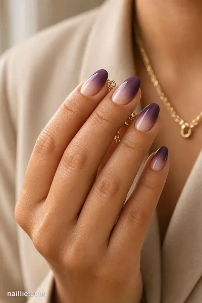 Close-up of short almond nails with a deep plum ombre fading into nude