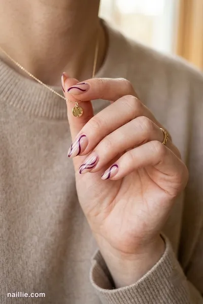 Close-up of oval nails with deep plum abstract swirls on a nude base — look 2