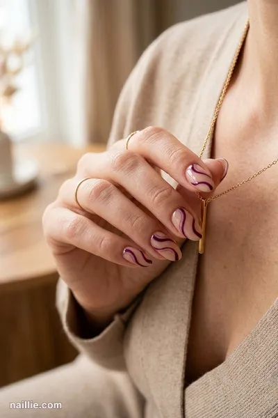 Close-up of oval nails with deep plum abstract swirls on a nude base — look 3