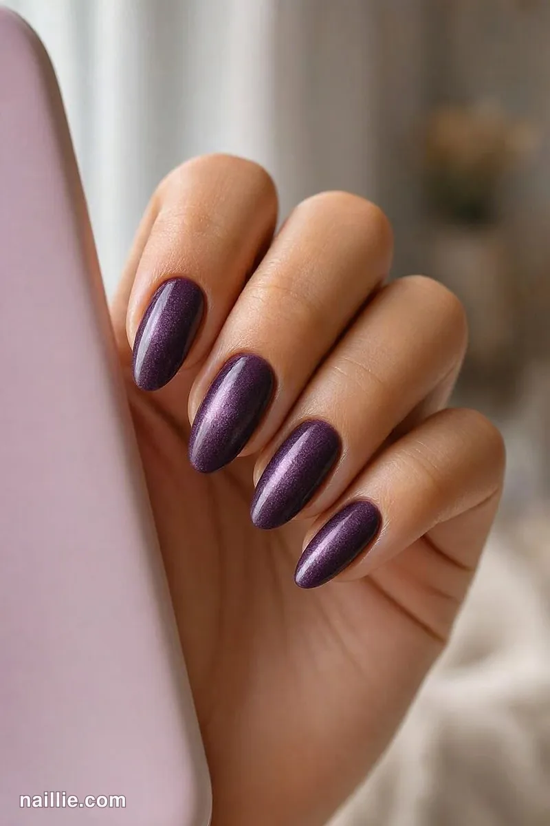 Close-up of almond nails with deep plum polish and a soft velvet shimmer