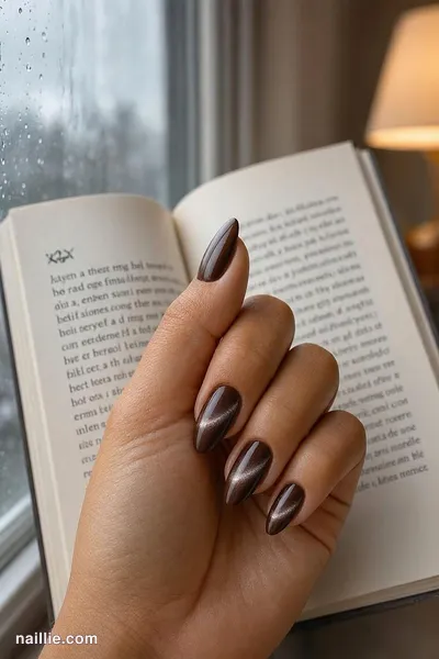 Close-up of almond nails with espresso brown polish and a shimmering magnetic cat eye effect — look 2
