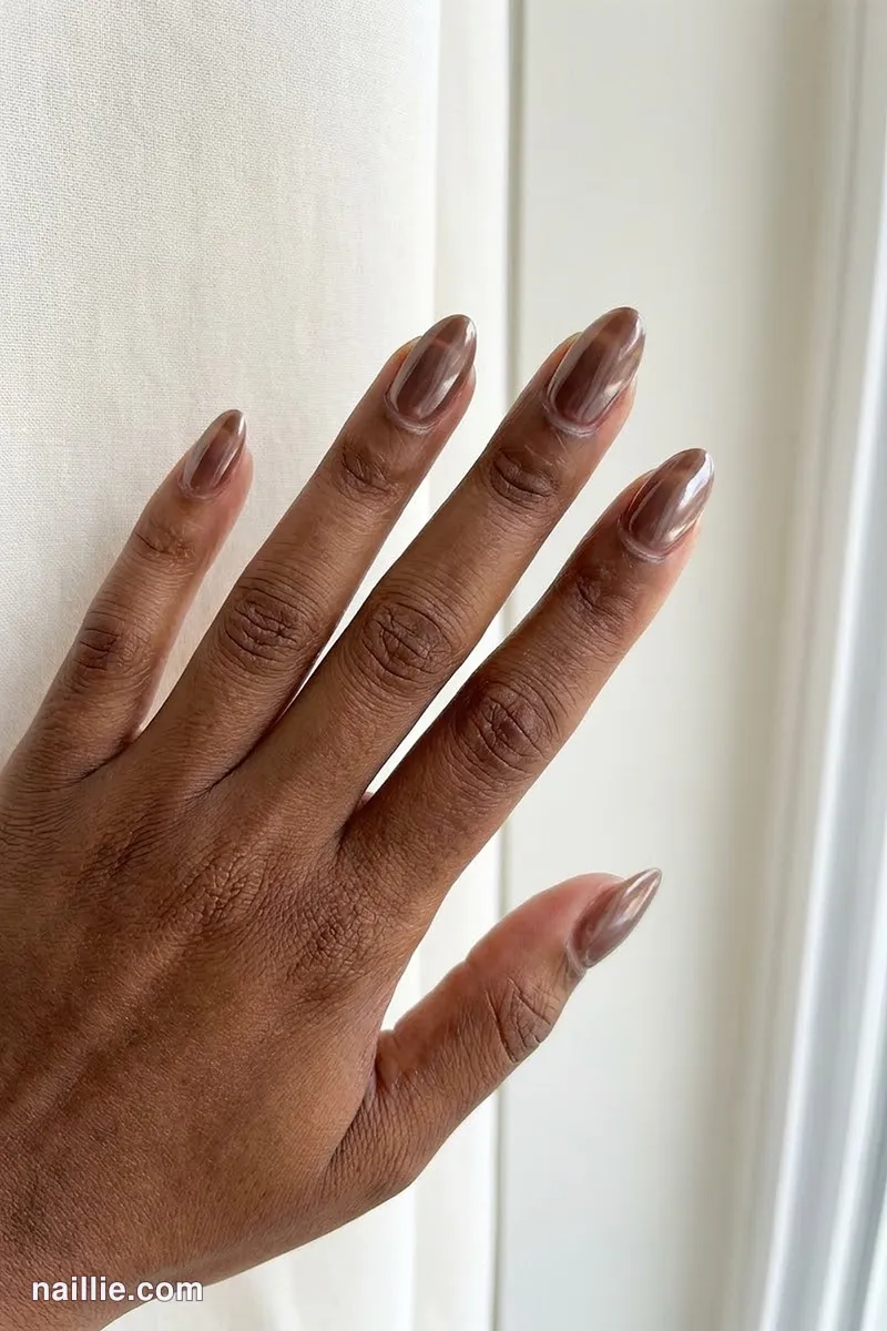Close-up of almond nails with espresso brown polish and a pearly glazed-donut shimmer