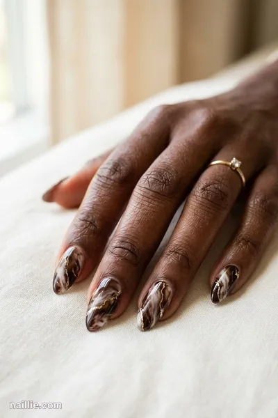 Close-up of almond nails with espresso brown marble swirls with gold veins — look 2