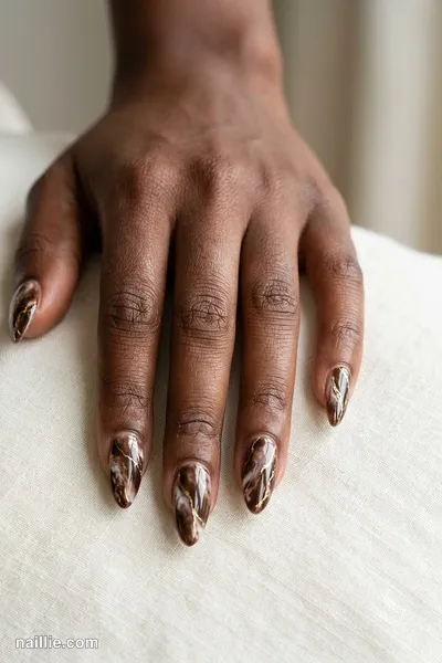Close-up of almond nails with espresso brown marble swirls with gold veins — look 3