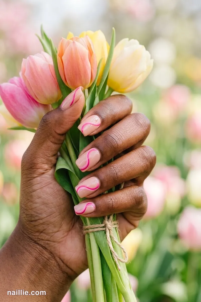 Close-up of short square nails with hot pink abstract swirls on a nude base