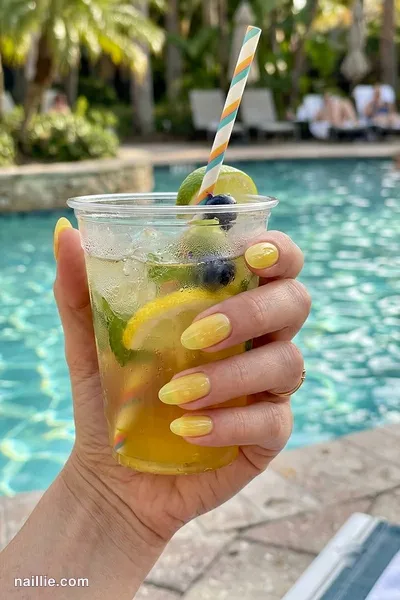 Close-up of oval nails with lemon yellow polish and a glossy see-through jelly finish