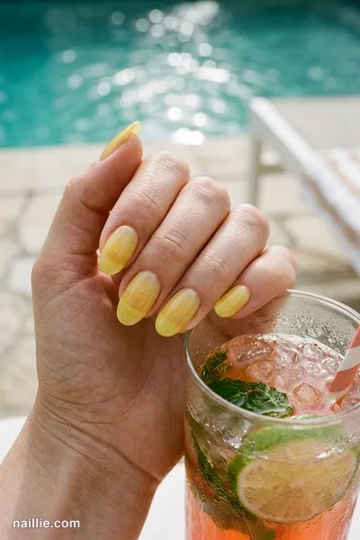 Close-up of oval nails with lemon yellow polish and a glossy see-through jelly finish — look 2