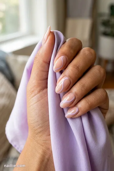 Close-up of oval nails with lilac abstract swirls on a nude base — look 3