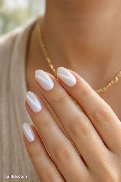Close-up of short almond nails with milky white polish and a shimmering magnetic cat eye effect — look 2