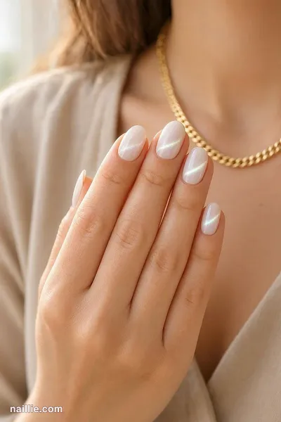 Close-up of short almond nails with milky white polish and a shimmering magnetic cat eye effect — look 3