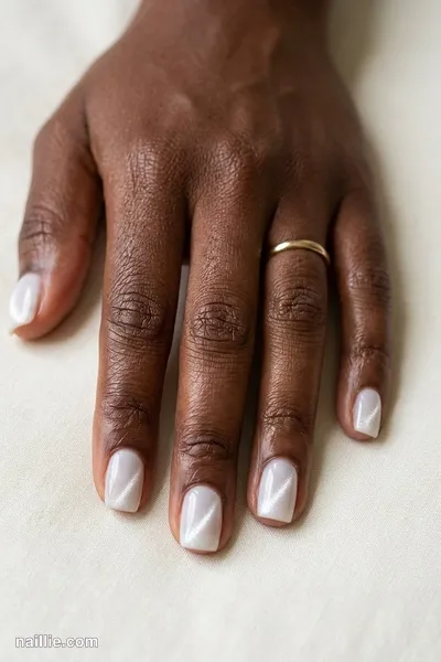 Close-up of squoval nails with milky white polish and a shimmering magnetic cat eye effect