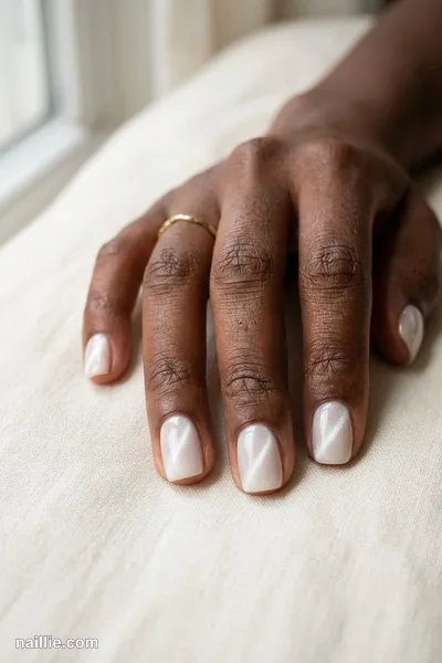 Close-up of squoval nails with milky white polish and a shimmering magnetic cat eye effect — look 3