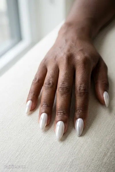 Close-up of almond nails with milky white polish and a mirror-like chrome finish
