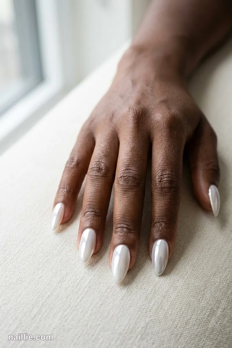 Close-up of almond nails with milky white polish and a mirror-like chrome finish