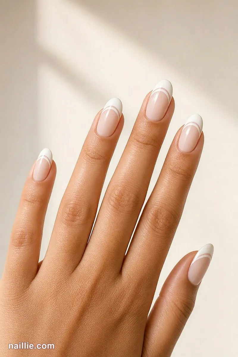 Close-up of almond nails with a milky white double French line