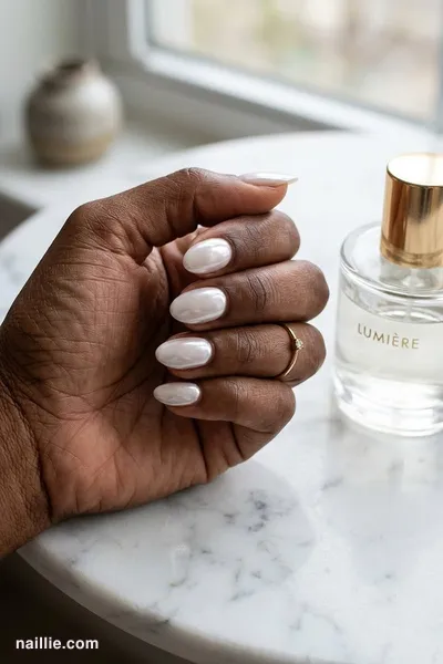 Close-up of short almond nails with milky white polish and a pearly glazed-donut shimmer — look 2